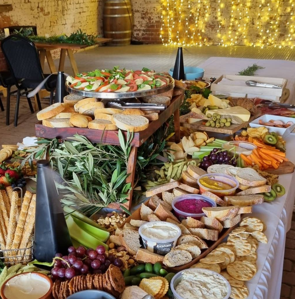 Long grazing table laid with cheeses, cured meats, fruit and dips under fairy lights